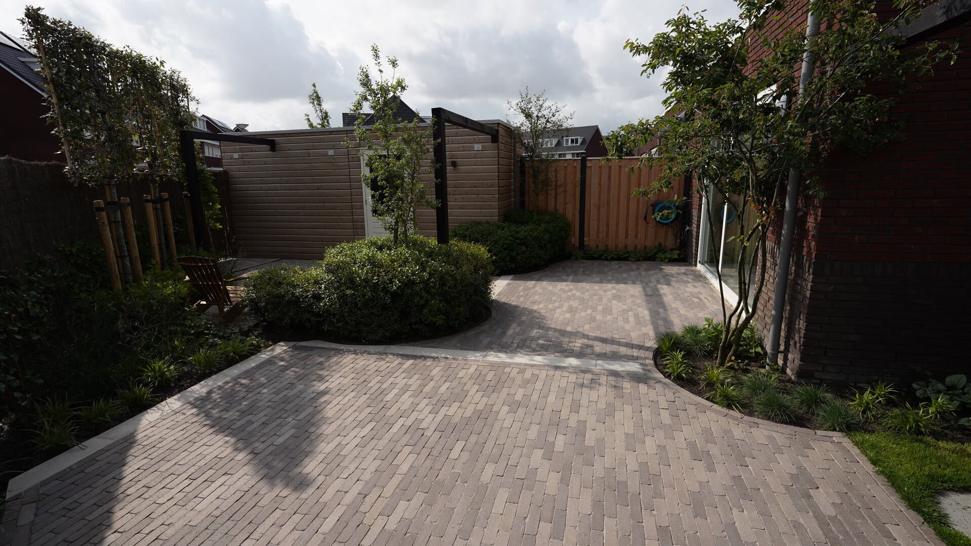 Achtertuin met terras en weelderige groene beplanting