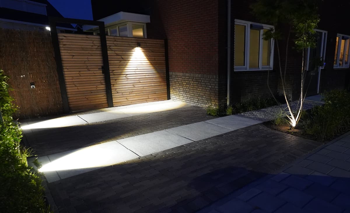 Sfeervol verlichte oprit en houten poort in de avond